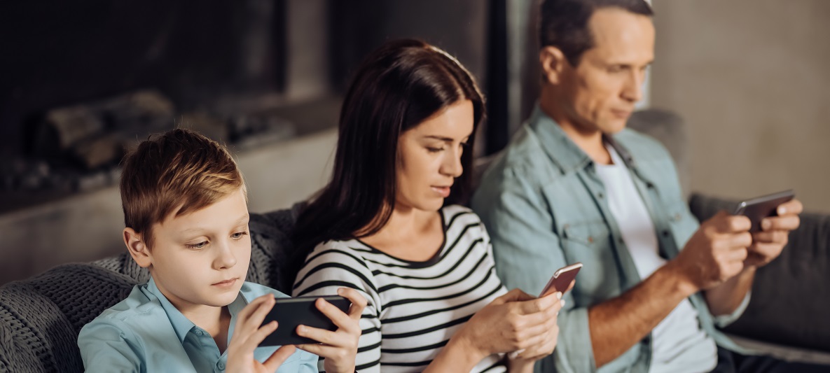 Eine Familie sitzt auf der Couch und jeder bedient sein Smartphone Eine Familie sitzt auf der Couch und jeder bedient sein Smartphone